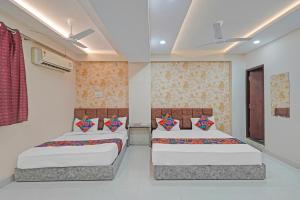 Dos camas en una habitación con paredes blancas. en FabHotel Elite Inn I, en Indore