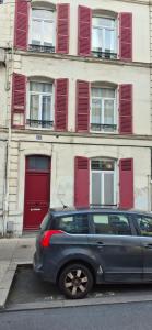 a car parked in front of a building with red doors at Le Parisien in Le Mans