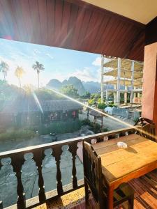 a balcony with a wooden table and a large window at Le Jardin 2 Organique Guesthouse Vang Vieng in Vang Vieng +39 photos