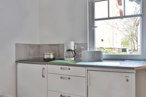 Bungalow Leuchtturm im Ostseeidyll am Waldrand في أوستسيباد نينهاجن: مطبخ أبيض مع طاولة مع نافذة +4 صور