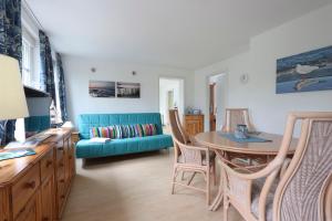 Bungalow Leuchtturm im Ostseeidyll am Waldrand في أوستسيباد نينهاجن: غرفة معيشة مع أريكة زرقاء وطاولة