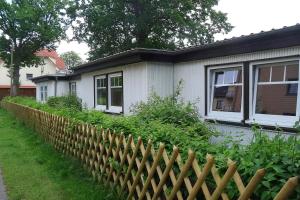Bungalow Robbe im Ostseeidyll am Waldrand في أوستسيباد نينهاجن: منزل أمامه سور خشبي