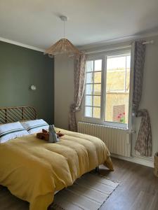 a bedroom with a bed with a yellow blanket and a window at Maison la belle vue in Nogent-le-Rotrou