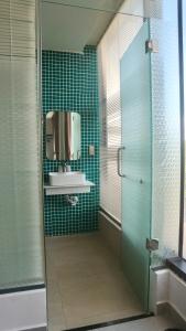 a green tiled bathroom with a sink and a mirror at Monstera Hotel and Coffee in Phú Quốc