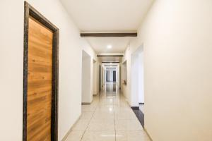 a hallway with white walls and a wooden door at Hotel O Meridian in Bijāpur