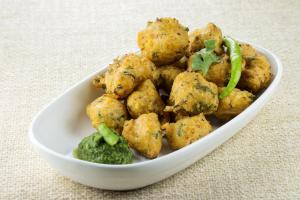 a white bowl of food with broccoli on a table at Hotel O Meridian in Bijāpur