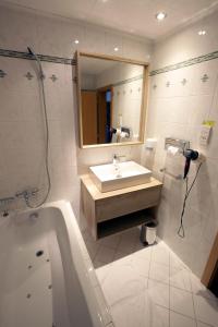 a bathroom with a sink and a tub and a mirror at Rodinný Hotel Hubert High Tatras in Vysoké Tatry