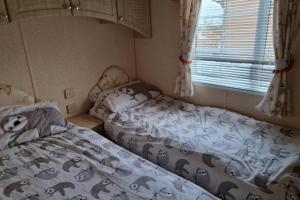 una piccola camera da letto con due letti e una finestra di Caravan - Sleeps 4 - Pet friendly - Parking a Newton Stewart
