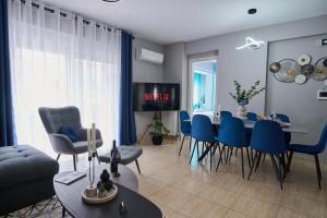 a living room with a table and blue chairs at V & S Downtown Apartment AXD in Alexandroupoli