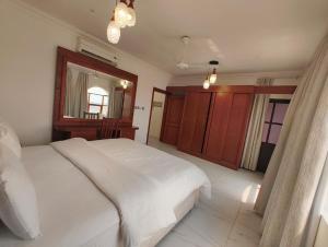 サラーラにあるAL-salam suitesの白いベッドと鏡のある寝室