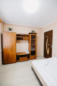 a bedroom with a bed and a wooden cabinet at B-G Apartments in Gheorgheni
