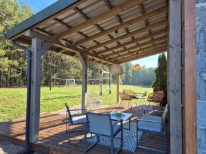 une pergola en bois avec une table et des chaises sur une terrasse dans l'établissement Szyszkowy Domek, à Milejczyce 24 autres photos