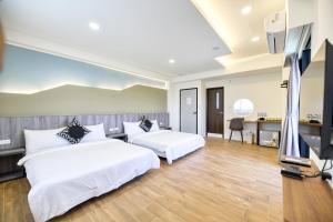 a bedroom with two beds and a flat screen tv at 覓海海景會館民宿 in Magong