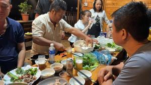 Kon Tum (2)にあるNhà Gỗ Homestay Măng Đenのテーブルの周りに座って食事をとる人々のグループ +20枚の写真