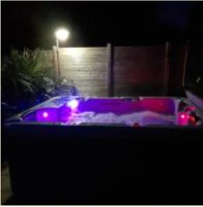 a hot tub with purple lights in a yard at night at Nuit etoile avec Jacuzzi prive in Fouesnant