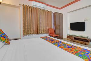 a bedroom with a bed and a tv and a chair at FabHotel Ajinkya Executive in Pune