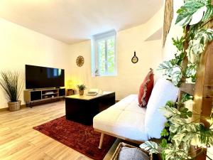 a living room with a white couch and a flat screen tv at Le Joyau d'Aristide - Appartement Confort en Hyper-Centre à deux pas du Théâtre Antique - Climatisation in La Celle-sous-Gouzon
