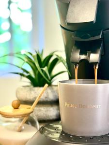 a coffee maker is making coffee in a cup at Le Joyau d'Aristide - Appartement Confort en Hyper-Centre à deux pas du Théâtre Antique - Climatisation in La Celle-sous-Gouzon