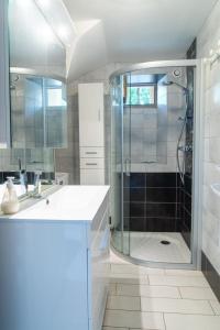 a white bathroom with a shower and a sink at Gîte La Maison Bleue 4/6 personnes in Saint-Étienne-du-Valdonnez