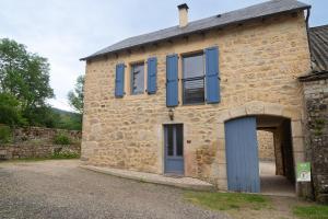 an old stone house with blue windows and a door at Gîte La Maison Bleue 4/6 personnes in Saint-Étienne-du-Valdonnez