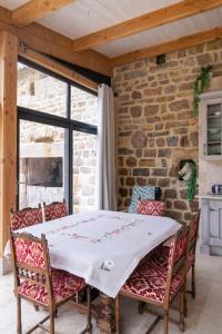 a table and chairs in a room with a stone wall at Gîte La Maison Bleue 4/6 personnes in Saint-Étienne-du-Valdonnez