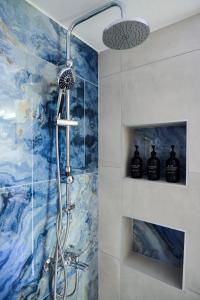 a shower in a bathroom with a blue and white wall at V & S Downtown Apartment AXD in Alexandroupoli