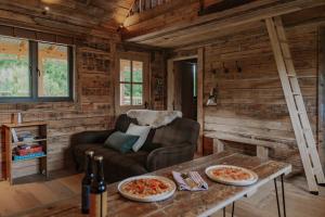 a living room with a couch and a table with pizza at Woolly Wood Cabins - Nant in Abbey-Cwmhir