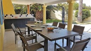 a wooden table and chairs on a patio at Superbe villa T4 classée 3 étoiles avec piscine privative chauffée 8PALCR in Saint Cyprien Plage