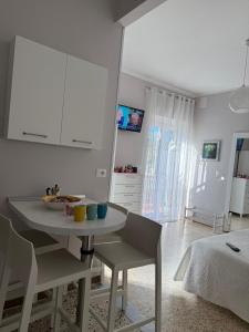 una cocina blanca con mesa y sillas en una habitación en PalinuroMonAmour Casa Vacanze, en Palinuro
