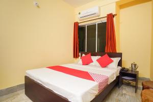 a bedroom with a bed with red pillows and a window at Hotel O Barman Guest House in Kolkata