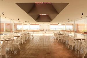 a dining room with tables and chairs and windows at Studio na Jatiuca in Maceió