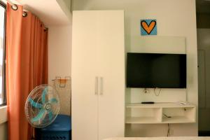 a white cabinet with a tv and a fan in a room at Studio na Jatiuca in Maceió