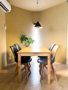 a dining room table with black chairs and a potted plant at Totono Amami in Karitachō