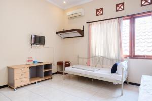 a room with a bed and a desk and a window at Urbanview Hotel Griya Surya Malang by RedDoorz in Malang