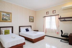 a hotel room with two beds and a window at Urbanview Hotel Griya Surya Malang by RedDoorz in Malang +62 photos