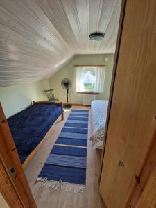 a bedroom with a bed with a blue comforter and a rug at Boende på SydKoster med havsutsikt och nära till bryggor in Strömstad