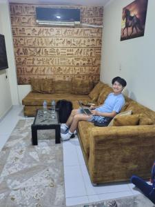 a man sitting on a couch with a laptop at Eyad Pyramids view in Cairo