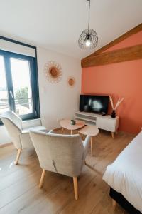 a room with a bed and a tv and a table at Vina Rhona - Studios de charme tout équipés entre Rhône et Vignobles de Condrieu in Condrieu