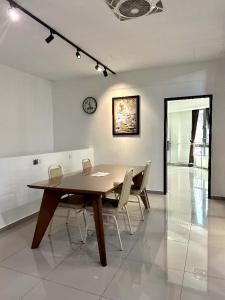 ein Esstisch mit Stühlen und einer Uhr an der Wand in der Unterkunft Jovial Boutique Hotel```` Kampung Baru in Bukit Mertajam