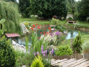 einen Garten mit einem Teich mit Blumen und einem Zaun in der Unterkunft Le Bocard in Thonnance-lès-Joinville