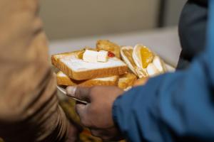 a person holding a plate of bread with butter and fruit at Nana Jungle Resort Near Chitwan National Park in Bharatpur