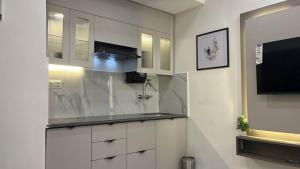 a kitchen with white cabinets and a flat screen tv at Cozyआश्रय 1BHK with peaceful balcony in Siroli