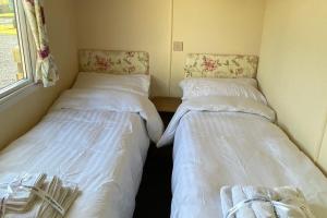 two beds in a small room with white sheets at Caravan - Sleeps 4 - Pet friendly - Parking in Newton Stewart