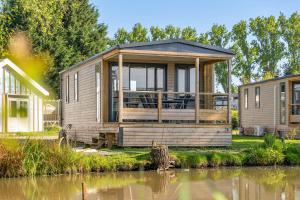 a modular home with a large deck next to a body of water at Family chalet Kinrooi - Papillon Kinrooi in Kinrooi