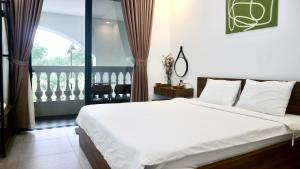a bedroom with a white bed and a balcony at Monstera Hotel and Coffee in Phú Quốc