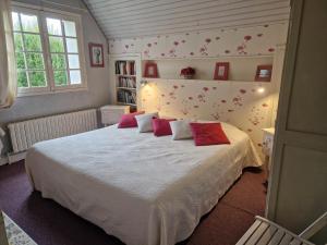 a bedroom with a large white bed with pink pillows at la MAISON de FRAMBOISE in Civray-de-Touraine
