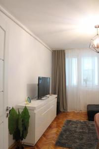 a white living room with a tv on a dresser at The Friendly Apartment in Turda