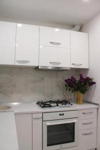 a white kitchen with a stove and a vase of flowers at The Friendly Apartment in Turda
