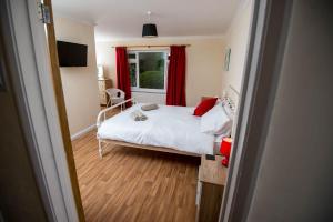 a bedroom with a bed and a window with red curtains at Round Park in Laugharne