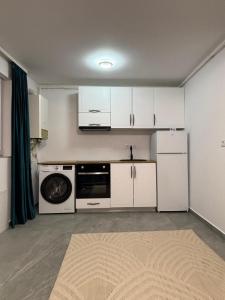 a kitchen with white cabinets and a washer and dryer at Cozy Apartment Mureseni in Târgu-Mureş +8 photos